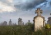 Foggy graveyard with tombstones and crosses under a cloudy sky