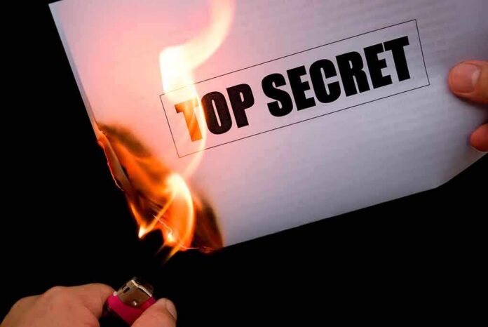 shutterstock_144202225 A hand holding a lighter igniting a paper labeled TOP SECRET as it catches fire