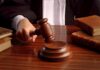 A judges hand holding a gavel over a wooden desk with law books