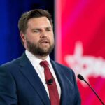 Generational Shift: Fresh Face Overthrows 11-Term Vet A man in a suit speaking at a podium during a conference
