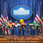 Logistics Delay Clouds High-Stakes U.S. Multiple microphones at White House press briefing podium.