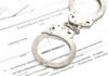 9–0 SMACKDOWN: Court Pushes Back Against Federal Case Handcuffs on top of an arrest warrant document.