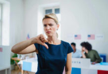 No FISA Renewal Without Voter ID — Standoff Woman with thumbs down in voting location.