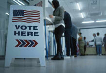 Sign reading Vote Here in a polling station.