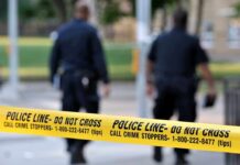 Alleged Domestic Stabbing Death Police officers walking past caution tape at a crime scene