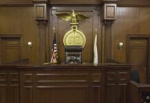 Supreme Court Lets 98-Year-Old Judge’s Suspension Stand Interior of a courtroom featuring a judges bench and American flag