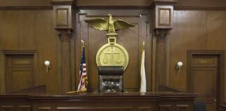 Interior of a courtroom featuring a judges bench and American flag