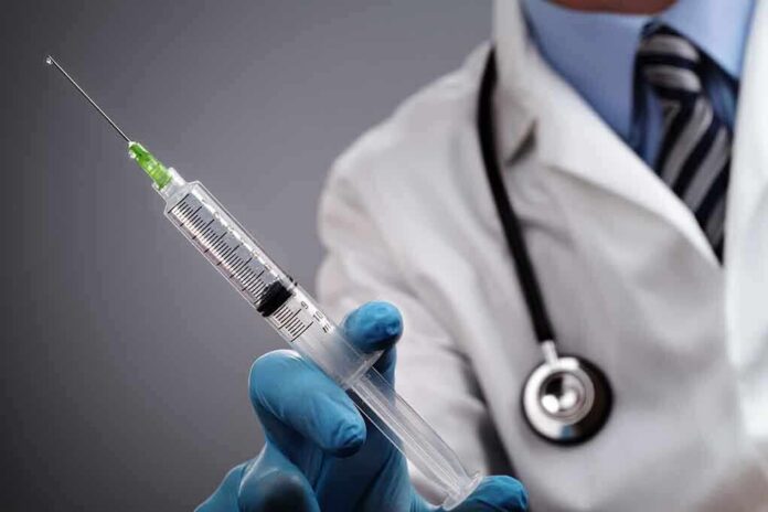 shutterstock_149167064 A doctor holding a syringe with a stethoscope around their neck