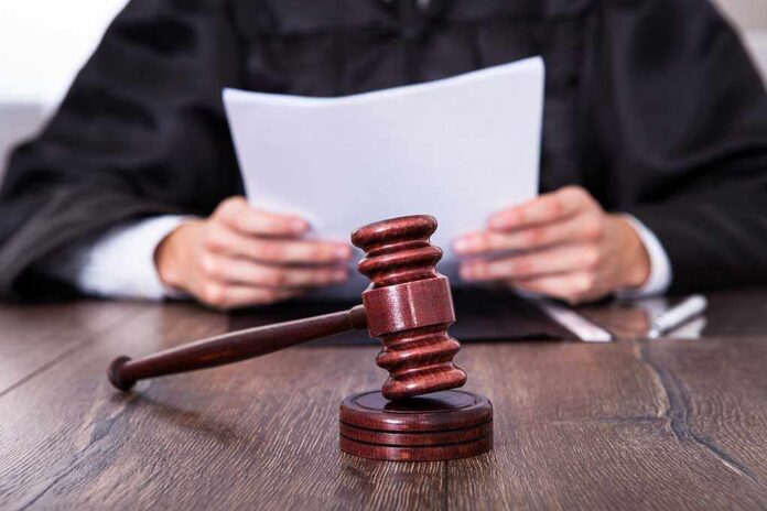 Close-up,Of,Male,Judge,In,Front,Of,Mallet,Holding,Documents A judge holding documents with a gavel in the foreground