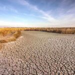 Red Alert Britain: Heat Dome Slams Europe A dry, cracked landscape with sparse grass and a blue sky