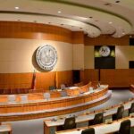 Rep. Kean’s 100+ Missed Votes Raise Questions Interior view of a government chamber with wooden paneling and seating