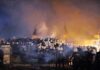 Turkey Locks Down Capital Before NATO Leaders Arrive A large crowd of police officers in helmets facing a smoky protest scene at night