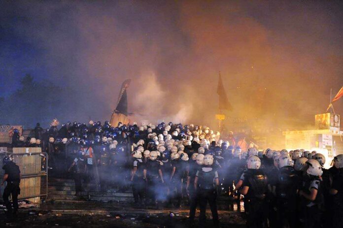 Istanbul,-,Jun,11:,In,Taksim,Gezi,Park,,Protests,Sparked A large crowd of police officers in helmets facing a smoky protest scene at night