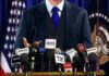 Trump Targets Veteran Reporter With “Maggot” Insult and Legal Threat A speaker at a press conference with multiple microphones in front of them