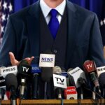 Trump Targets Veteran Reporter With “Maggot” Insult and Legal Threat A speaker at a press conference with multiple microphones in front of them