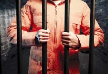 PARDON TWIST: Prison Story Still Fuels Debate Over Corruption and Politics Person in an orange jumpsuit gripping prison bars in a dark cell