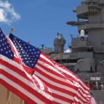 Hellfire Missile Halts Cargo Ship in Gulf of Oman as Naval Tensions Surge American flags in front of a naval ship under a blue sky