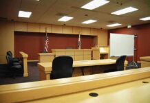 Trade Ruling Opens Door to Billions in Tariff Refund Claims Interior view of an empty courtroom with wooden furniture and American flags