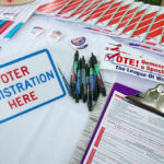 Voter registration table with forms, pens, and brochures.