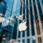 Court Fight Erupts Over Apple’s Claims Apple store with glass facade and city reflections.