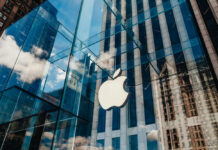 Court Fight Erupts Over Apple’s Claims Apple store with glass facade and city reflections.