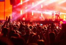 Star-Studded Wedding Reports Put Adam Sandler Center Stage Crowd at concert with vibrant stage lights.