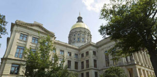 Historic building with a gold dome and surrounding trees.
