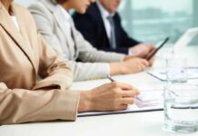 Government Efficiency Agency Ends as Debate Over Savings Intensifies Close-up of hands in business attire during a meeting, writing notes and reviewing documents
