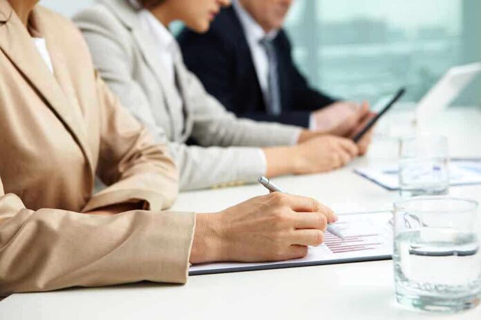 shutterstock_103051145 Close-up of hands in business attire during a meeting, writing notes and reviewing documents