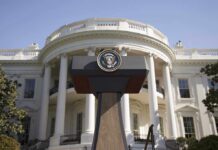 Press podium with presidential seal in front of the White House