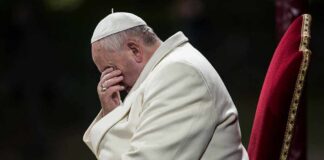 Pope sitting with his head bowed and hand covering his face