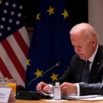 Pressure, Diplomacy, and No Clear Endgame elderly man at conference table with flags in background