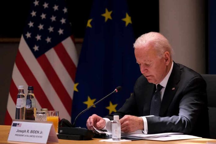 elderly man at conference table with flags in background