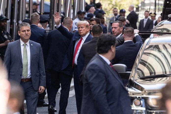 shutterstock_2284766695 Man in suit waves while surrounded by security detail on a city street