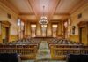 Interior view of a historic courtroom with wooden furnishings and chandeliers