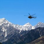 Helicopter flying over snow-capped mountain range