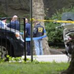 law enforcement officers gather at taped-off outdoor scene