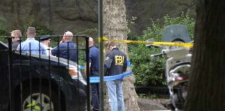 law enforcement officers gather at taped-off outdoor scene