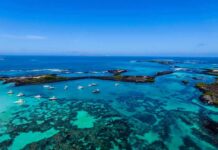 The Viral Dive That Nearly Ended in Tragedy Boats anchored in turquoise lagoon with rocky islets