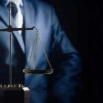Scales of justice held by a person in a suit