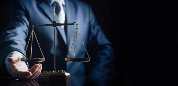 shutterstock_1025566252 Scales of justice held by a person in a suit