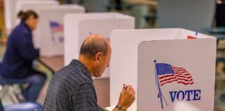 Man filling out ballot at voting booth