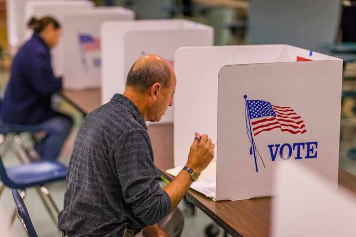 shutterstock_1046168680 Man filling out ballot at voting booth