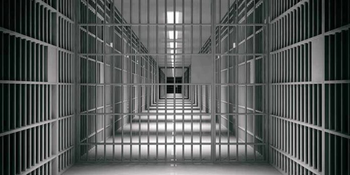shutterstock_1118920109 empty prison corridor with barred cells