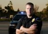 Officer’s Gun Targeted in Shocking Virginia Incident police officer standing with arms crossed in front of patrol car