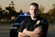 Officer’s Gun Targeted in Shocking Virginia Incident police officer standing with arms crossed in front of patrol car