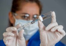 Healthcare worker draws vaccine from vial with syringe