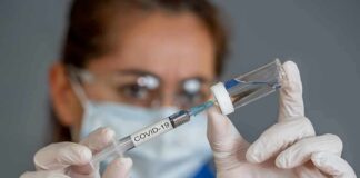 Healthcare worker draws vaccine from vial with syringe