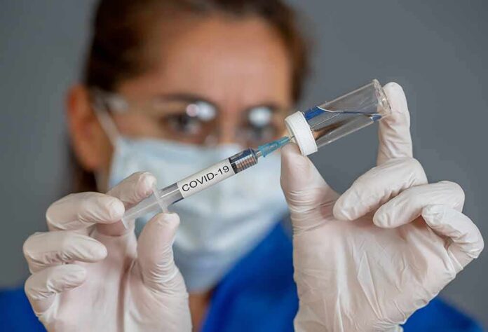 shutterstock_1708463248 Healthcare worker draws vaccine from vial with syringe