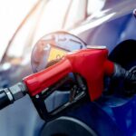 Red gasoline nozzle fueling a blue car